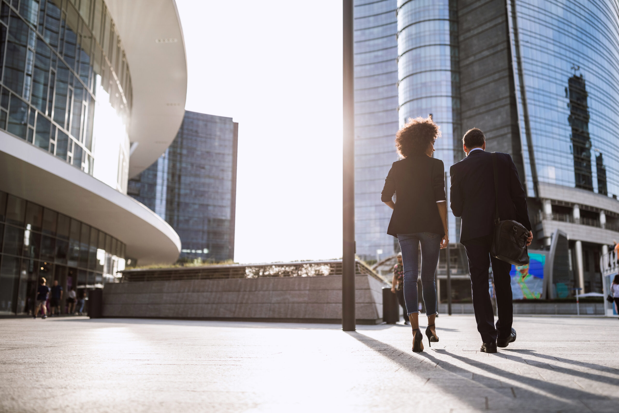 Two Professionals Walking In Front of Buildings