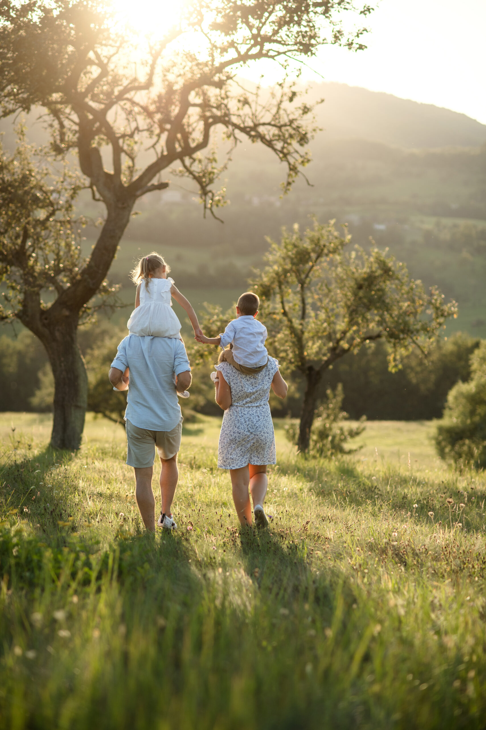 Parents Carrying their Children in a Meadow
