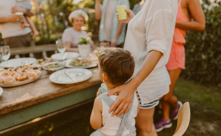 Family Standing Around a Table Eating Food