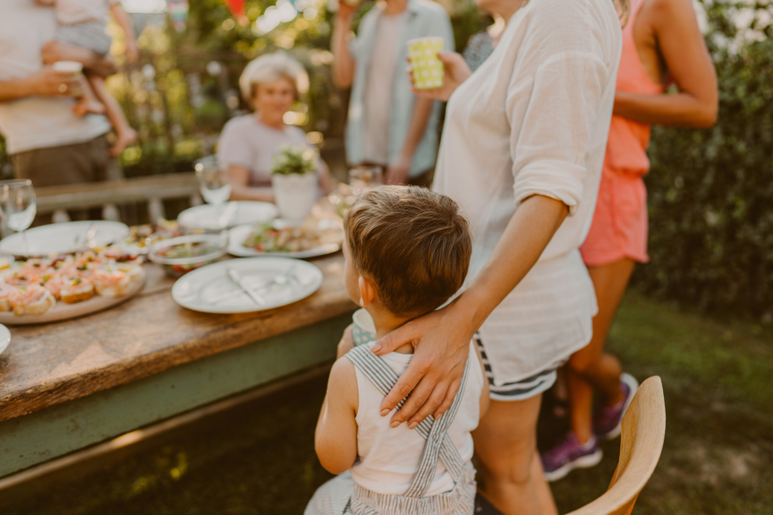 Family Standing Around a Table Eating Food