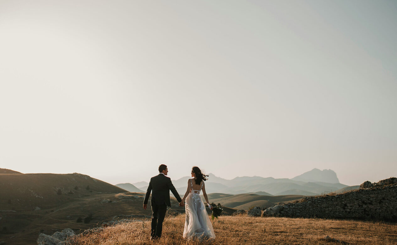 Just-married couple walking away into a scenic landscape